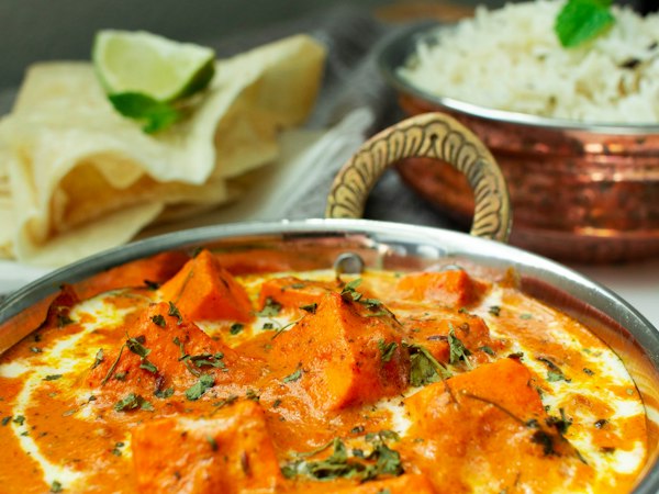 Paneer butter masala in a copper handi with rice and roti